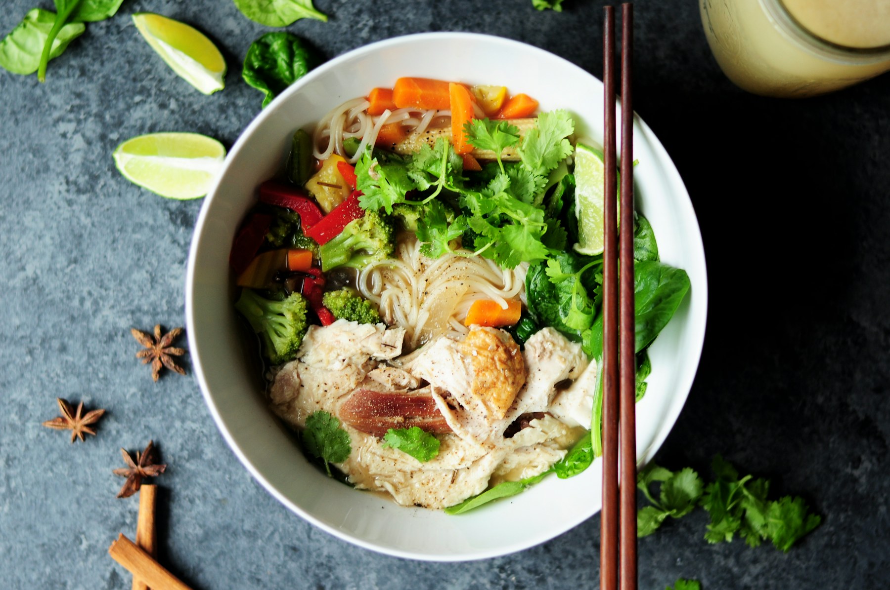 Bowl of phở with lime, herbs and chopsticks